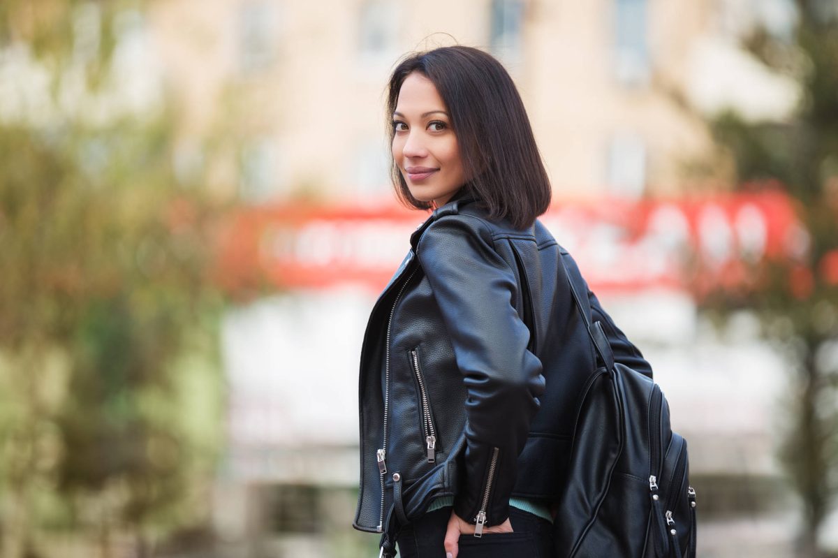Young fashion woman in black leather jacket walking in city stre