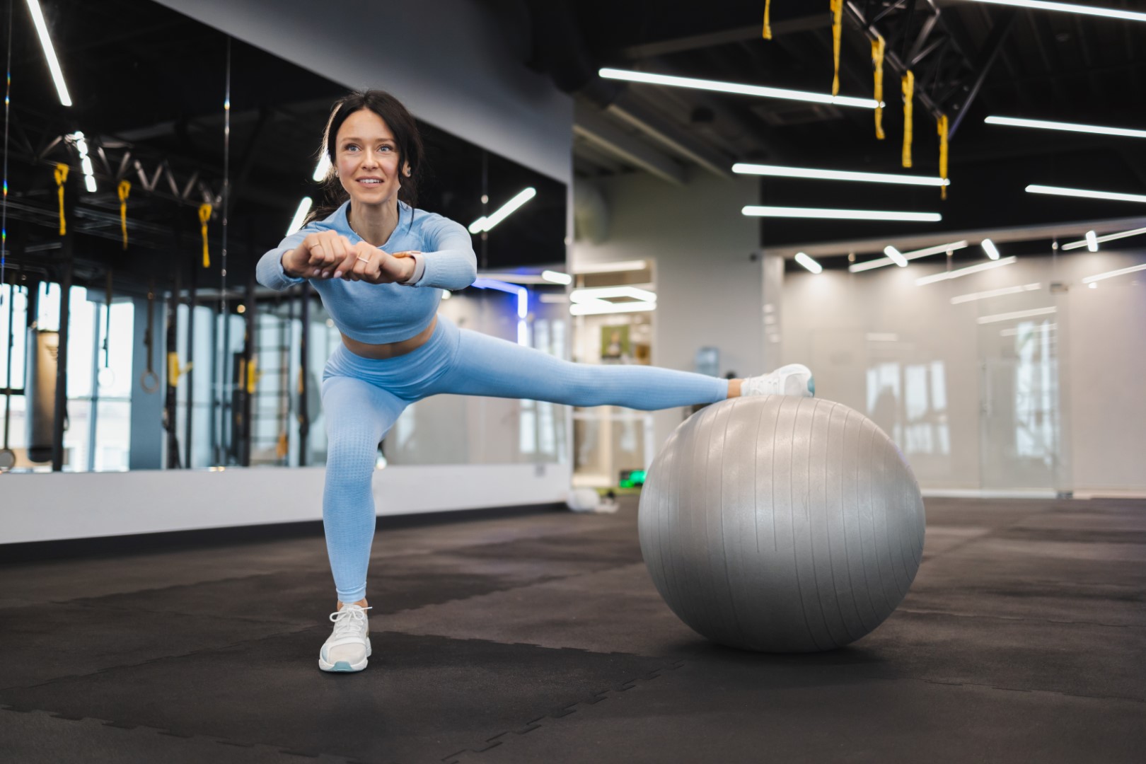 Cheerful woman working out with a fitness ball in the gym