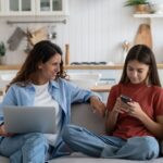 Young smiling modern mother talking to child daughter about online safety
